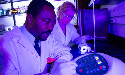Chukuka S. Enwemeka, dean of UWM’s College of Health Sciences, conducts an experiment with research associate Daniela Masson-Meyers. Enwemeka is internationally known for his work in phototherapy. Among his discoveries: blue light in a certain wavelength kills the antibiotic-resistant “superbug” form of Staphylococcus aureus. Image: Photo by Troye Fox