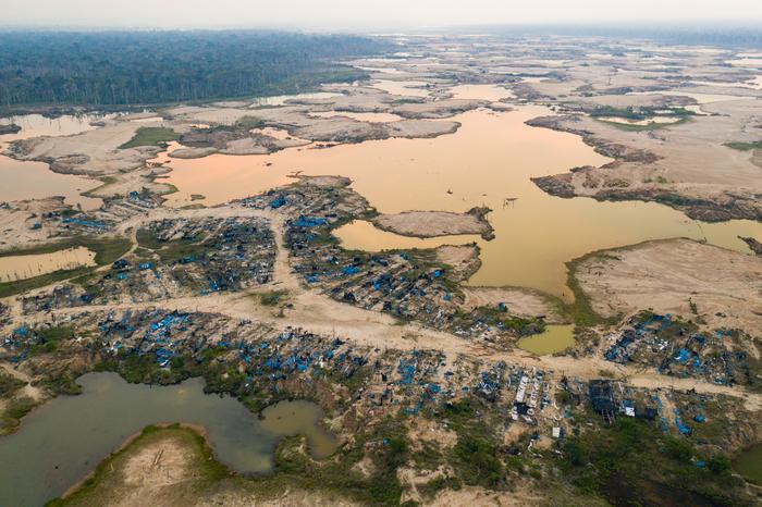 A former mining camp shows where shallow mining ponds have overwhelmed a former river system in the La Pampa region of Madre de Dios, Peru