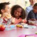 Four children eat packed lunches together.