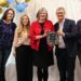 Mary Beckerle and Brad Cairns hold the Vineyard Cares Business of the Year plaque with Mayor Julie Fullmer and others.