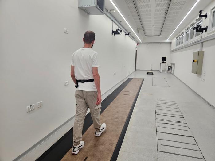 A person walking in a state-of-the-art gait lab, with a wearable sensor positioned on his lower back.