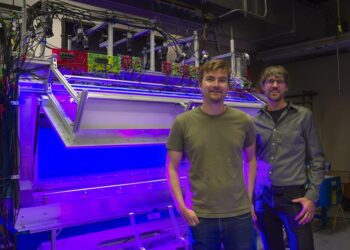 Postdoctoral researcher David Stupski, left, and Assistant Professor Floris van Breugel stand in front of a wind tunnel at the University of Nevada, Reno.